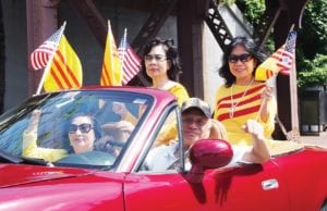 Vietnamese-American Community of Massachusetts members ride and wave flags in the Dorchester Day Parade. Banner Photo