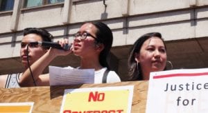 Minh Do addresses demonstrators in front of the John F. Kennedy Federal Building on City Hall Plaza. Banner photo