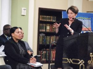 Attorney General Maura Healey talks about immigration and healthcare, as Suffolk County District Attorney candidate Rachael Rollins waits on stage for her turn to speak.Banner Photo